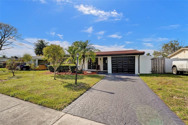 view of front of home featuring a garage, fence, decorative driveway, a front yard, and stucco siding