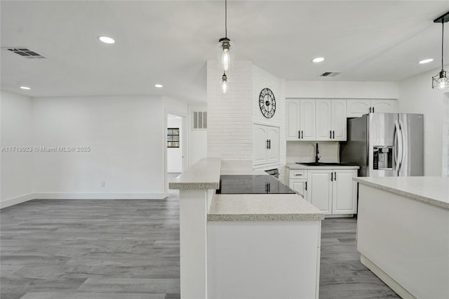 kitchen featuring visible vents, white cabinets, a peninsula, stainless steel refrigerator with ice dispenser, and a sink