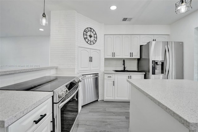 kitchen with stainless steel appliances, a sink, visible vents, white cabinetry, and light wood-type flooring