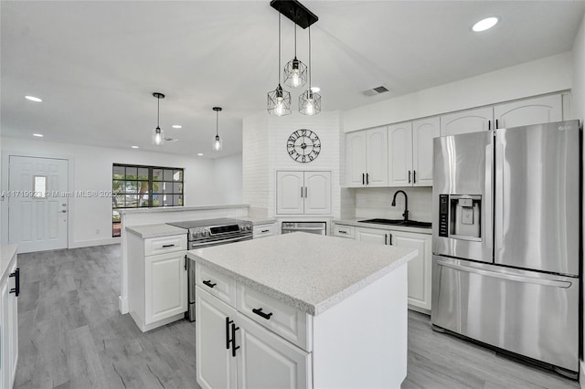 kitchen with visible vents, appliances with stainless steel finishes, a sink, a kitchen island, and a peninsula