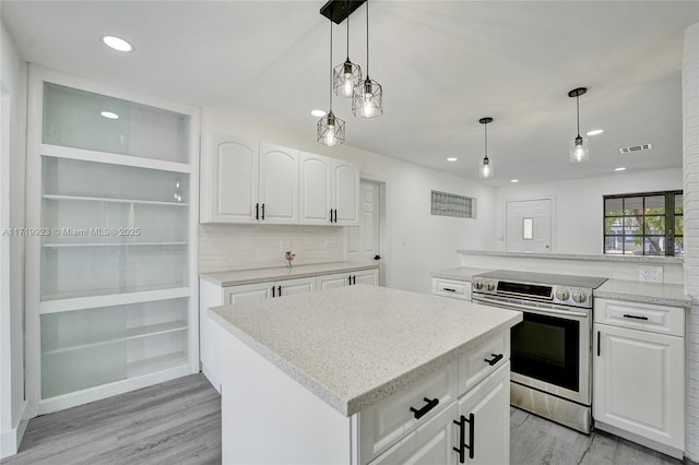 kitchen featuring a center island, white cabinets, stainless steel range with electric cooktop, and visible vents