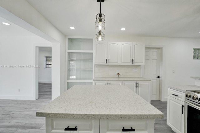 kitchen featuring pendant lighting, a center island, white cabinetry, and stainless steel range with electric stovetop