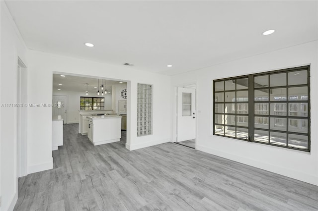 unfurnished living room with light wood-type flooring, visible vents, baseboards, and recessed lighting