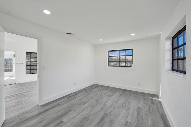 unfurnished room with recessed lighting, wood finished floors, visible vents, and baseboards