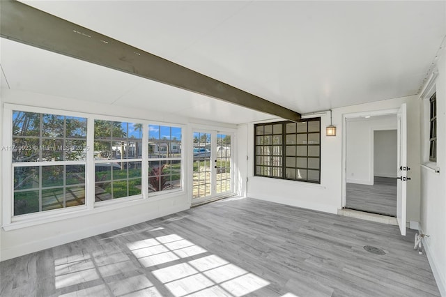 unfurnished sunroom featuring beamed ceiling