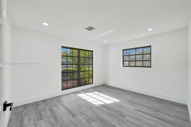 spare room with baseboards, wood finished floors, and a healthy amount of sunlight