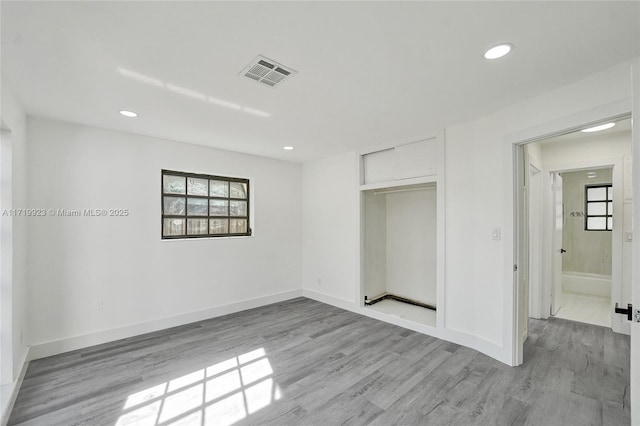 unfurnished bedroom featuring ensuite bath, a closet, and light hardwood / wood-style flooring