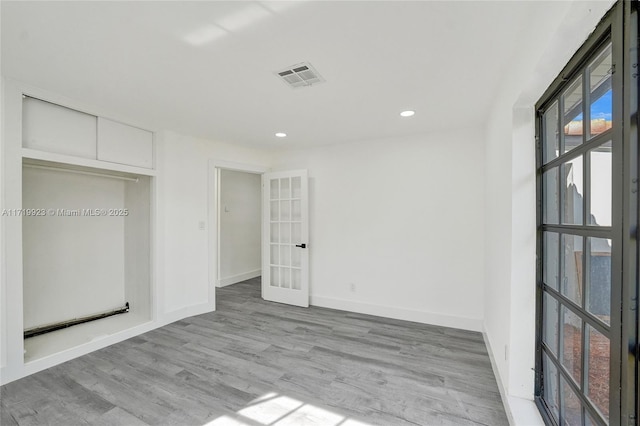 unfurnished bedroom featuring french doors, light wood-type flooring, and a closet