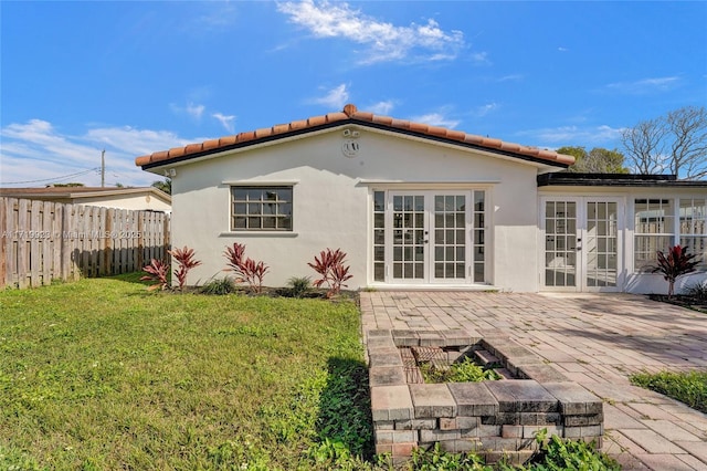 rear view of house featuring a lawn, fence, french doors, a patio area, and stucco siding