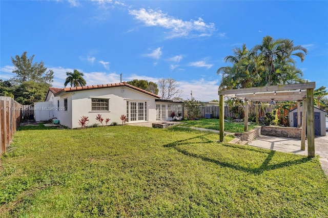 back of house featuring an outbuilding, a yard, french doors, and a fenced backyard