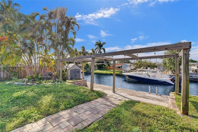 view of dock with boat lift, a lawn, a water view, and fence