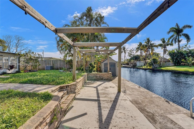 view of patio featuring a water view, an outdoor structure, fence, and a shed