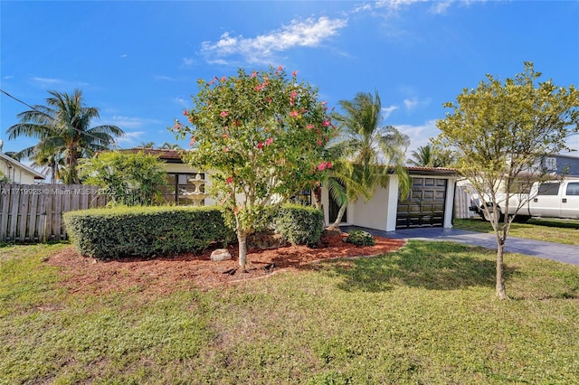 obstructed view of property with stucco siding, fence, a garage, driveway, and a front lawn