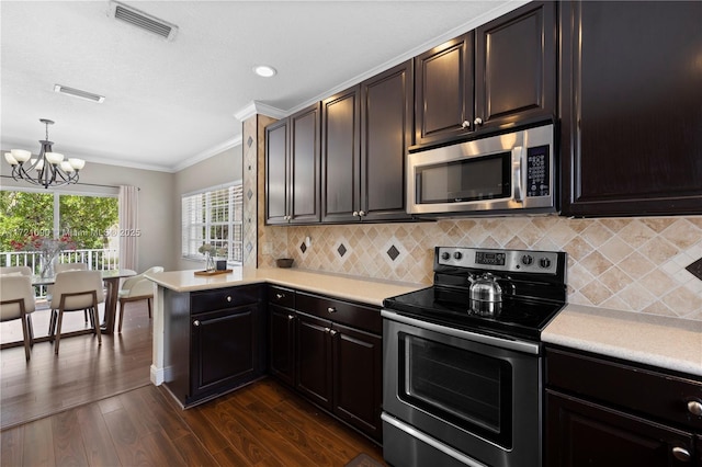 kitchen featuring backsplash, crown molding, appliances with stainless steel finishes, decorative light fixtures, and a chandelier