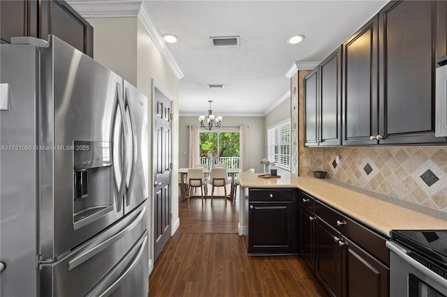 kitchen featuring an inviting chandelier, ornamental molding, appliances with stainless steel finishes, decorative light fixtures, and kitchen peninsula