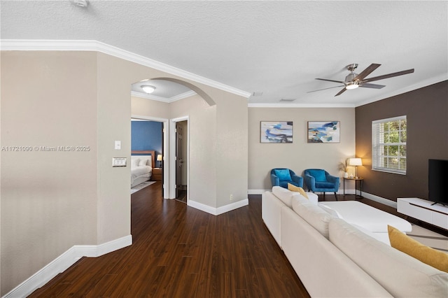 unfurnished living room featuring crown molding, ceiling fan, dark wood-type flooring, and a textured ceiling