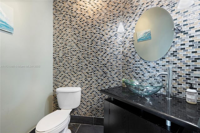 bathroom with decorative backsplash, vanity, tile walls, tile patterned flooring, and toilet