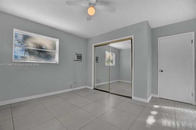 unfurnished bedroom featuring an AC wall unit, ceiling fan, a closet, and light tile patterned flooring