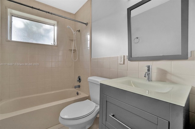 full bathroom with tiled shower / bath combo, toilet, decorative backsplash, vanity, and tile walls