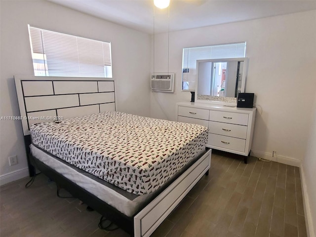 bedroom with dark wood-type flooring, a wall unit AC, and multiple windows