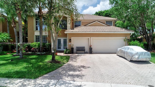 mediterranean / spanish-style home featuring french doors, a garage, and a front lawn