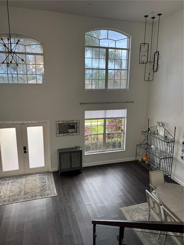 living room featuring an inviting chandelier, dark hardwood / wood-style floors, french doors, and a healthy amount of sunlight