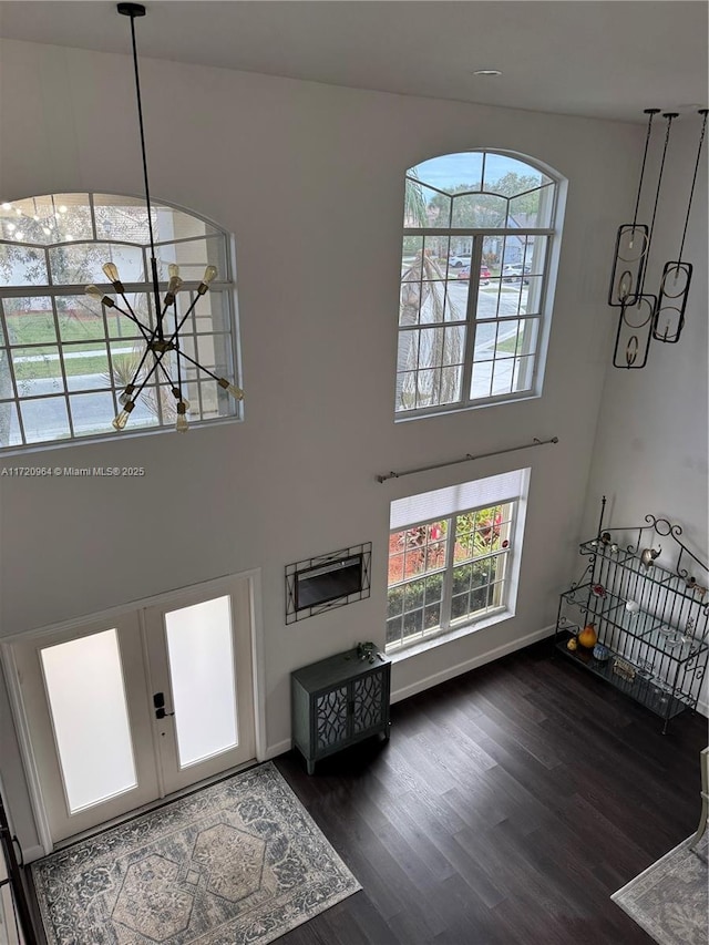 foyer featuring french doors, dark hardwood / wood-style floors, a high ceiling, and a notable chandelier