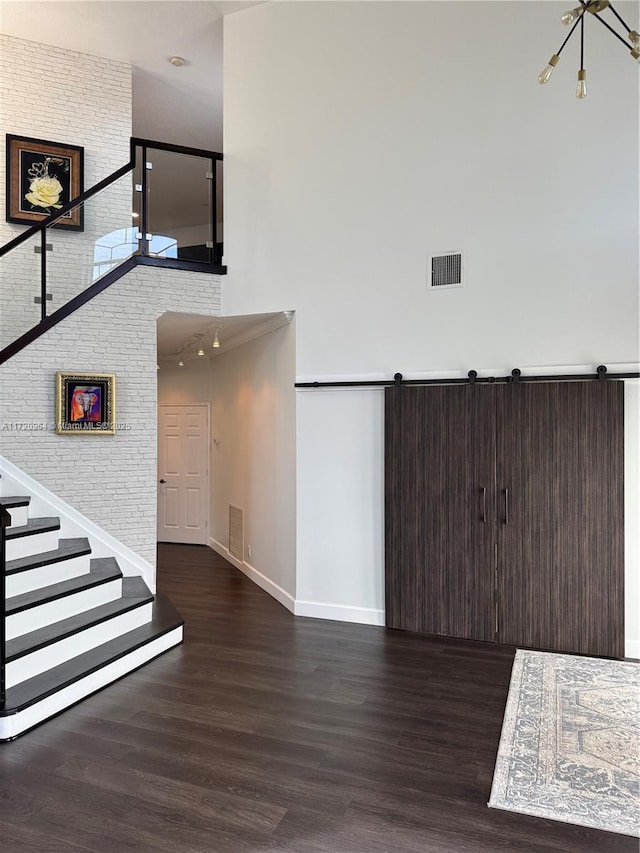 interior space featuring brick wall, a barn door, and hardwood / wood-style floors