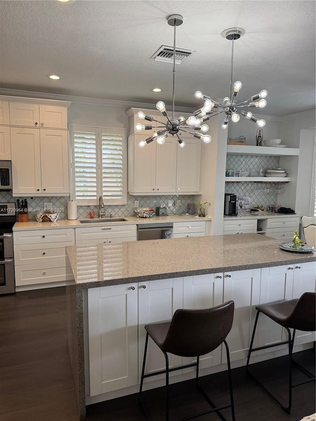 kitchen with stainless steel appliances, light stone countertops, sink, and white cabinets