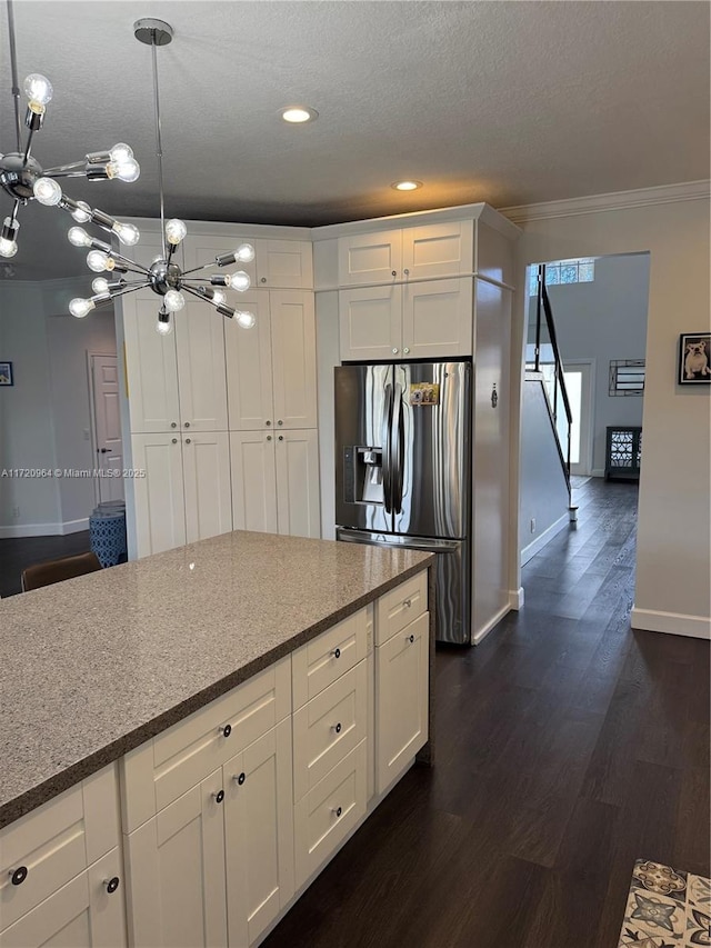 kitchen featuring white cabinets, crown molding, stainless steel fridge, and decorative light fixtures