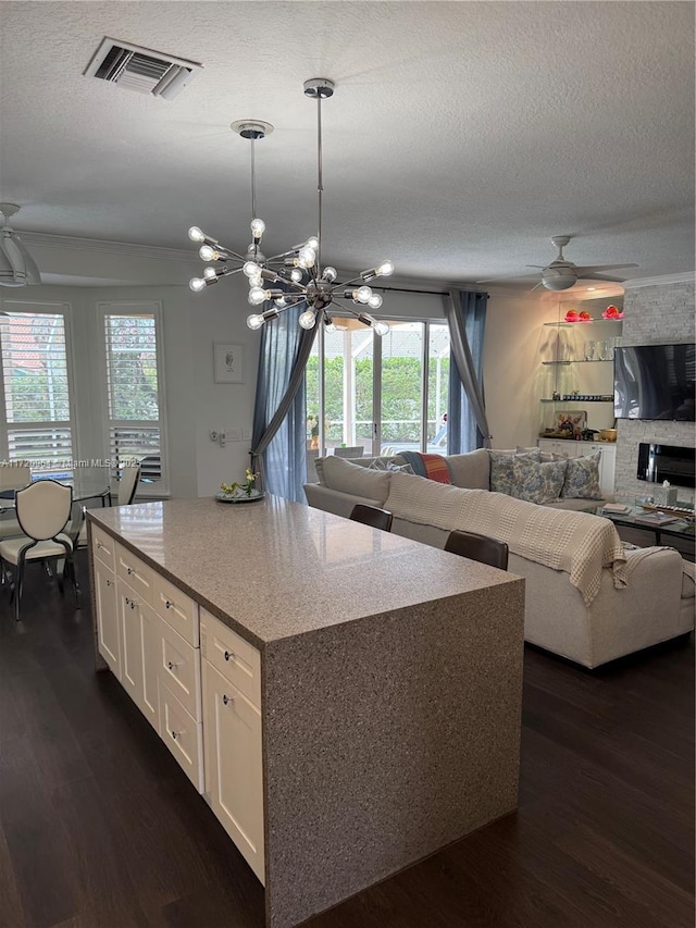 kitchen featuring ceiling fan with notable chandelier, a center island, a wealth of natural light, and white cabinets