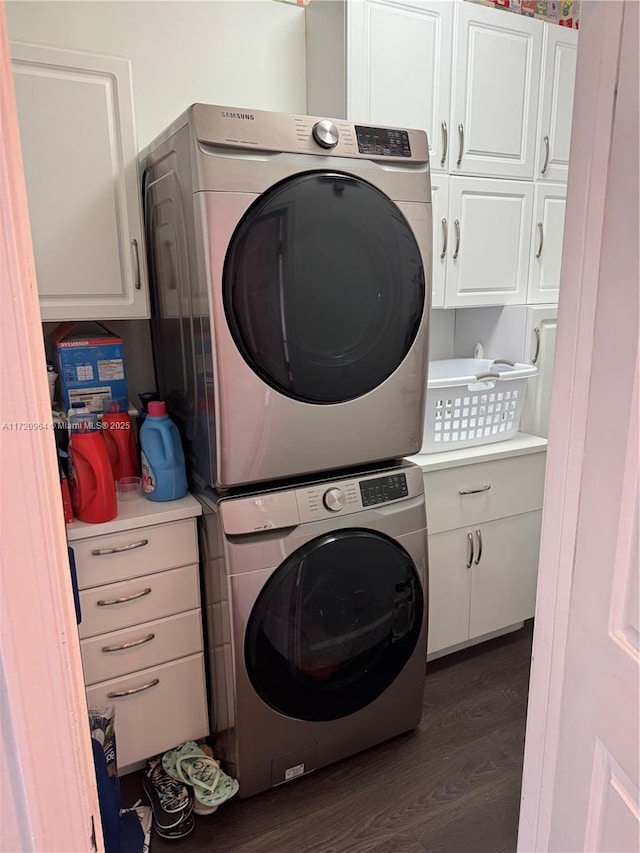 clothes washing area with cabinets, stacked washer / dryer, and dark hardwood / wood-style floors