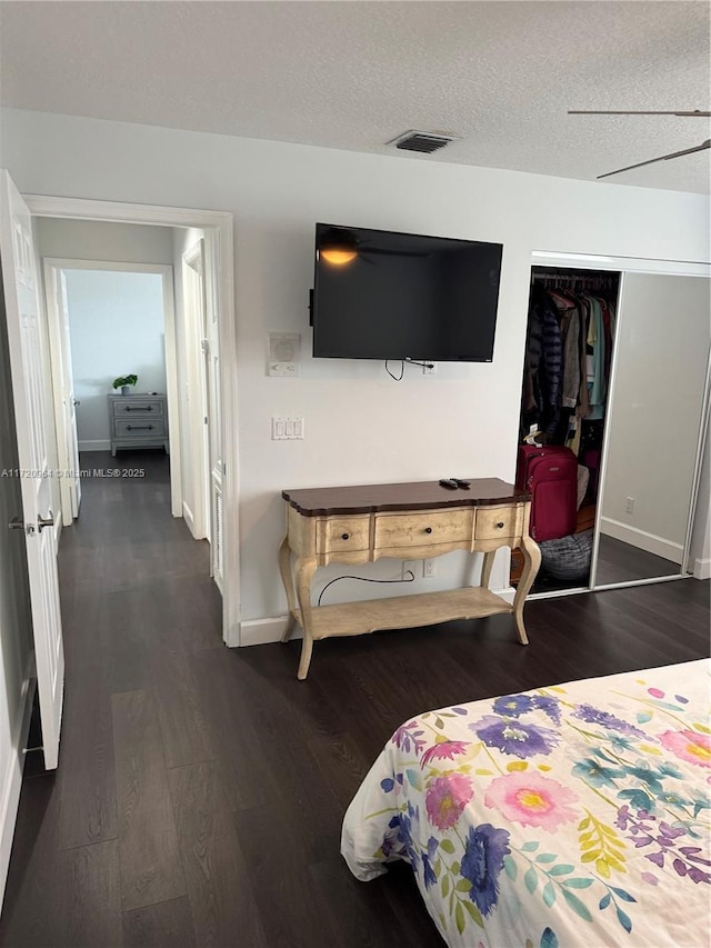 bedroom with a textured ceiling, dark hardwood / wood-style flooring, and a closet