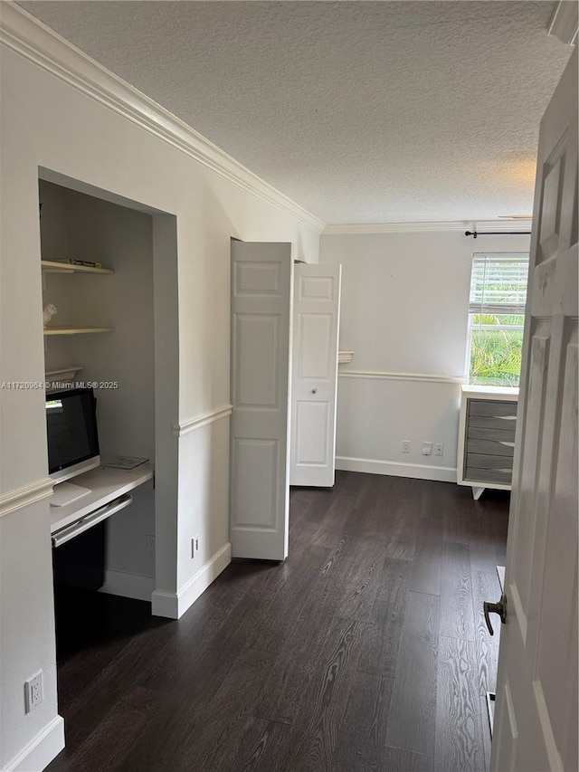 interior space with dark wood-type flooring, ornamental molding, and a textured ceiling