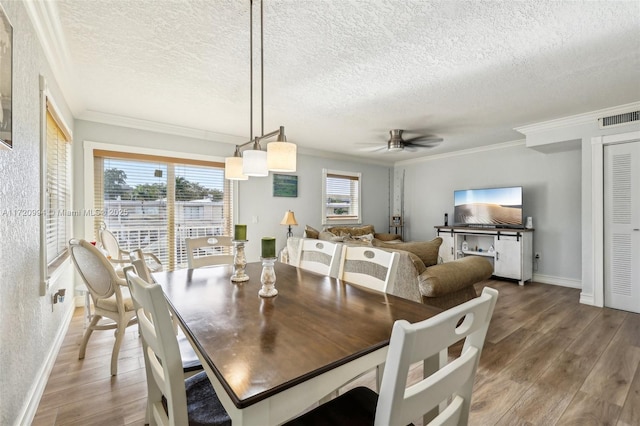 dining area with hardwood / wood-style flooring, ceiling fan, crown molding, and a textured ceiling