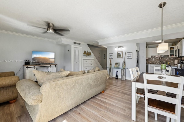 living room featuring light hardwood / wood-style flooring, ceiling fan, and crown molding