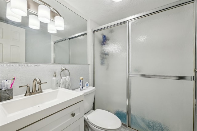 bathroom with walk in shower, backsplash, vanity, and toilet