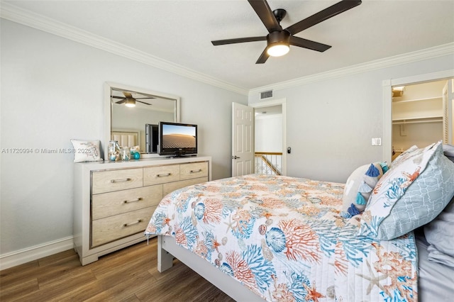 bedroom featuring a spacious closet, ceiling fan, dark wood-type flooring, crown molding, and a closet