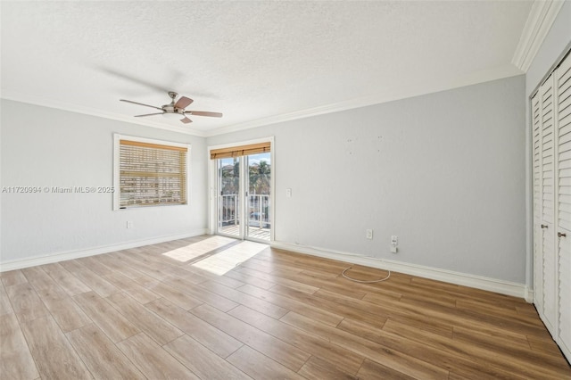 unfurnished room featuring ceiling fan, light wood-type flooring, a textured ceiling, and ornamental molding