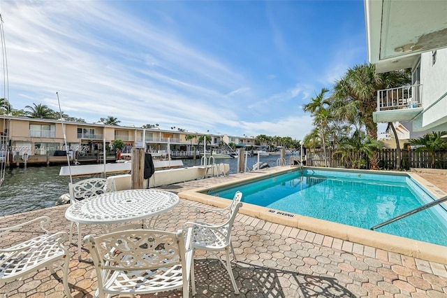 view of swimming pool with a water view, a patio, and a boat dock