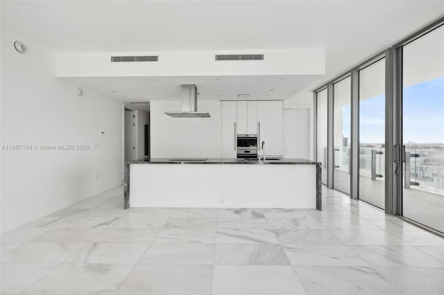 kitchen with white cabinetry, a healthy amount of sunlight, range hood, and a wall of windows