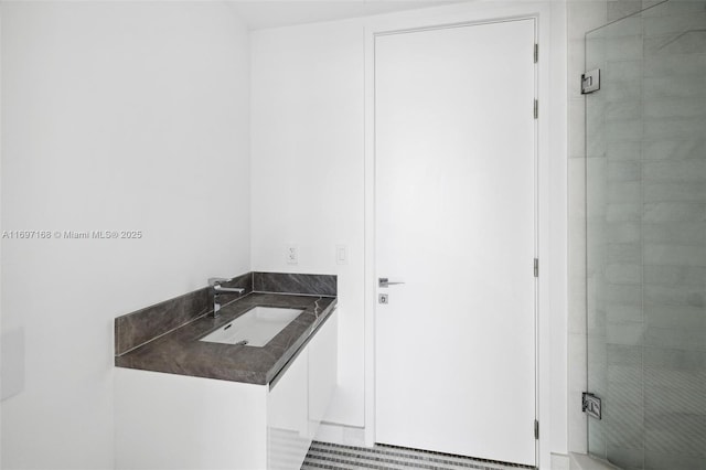 bathroom featuring a shower with shower door and sink