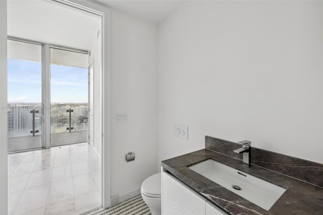 bathroom with tile patterned floors, vanity, expansive windows, and toilet