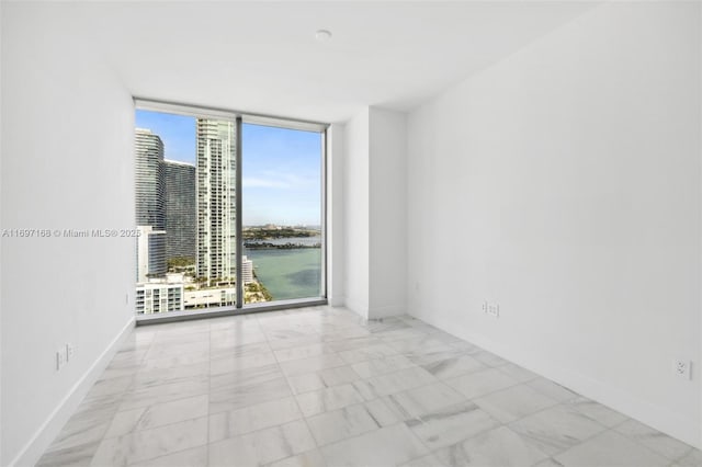 unfurnished room featuring a water view and floor to ceiling windows