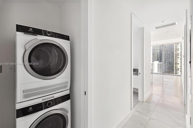 clothes washing area featuring light tile patterned floors and stacked washer / dryer