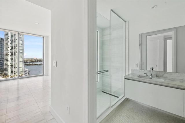 bathroom featuring floor to ceiling windows, tile patterned floors, a water view, a shower with door, and vanity