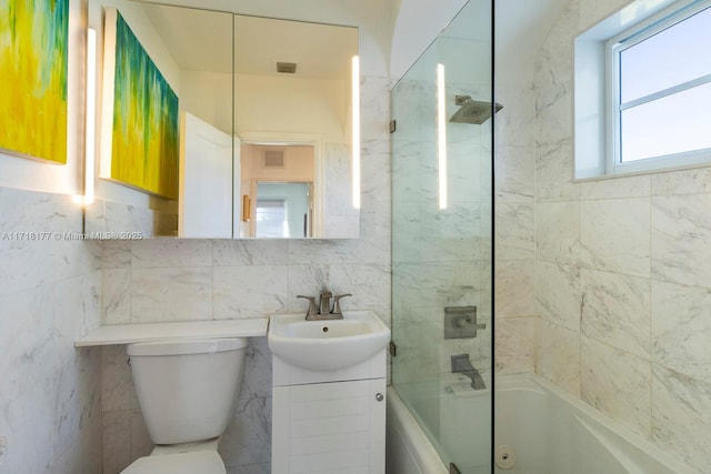 full bathroom with tile walls, vanity, tiled shower / bath combo, and toilet