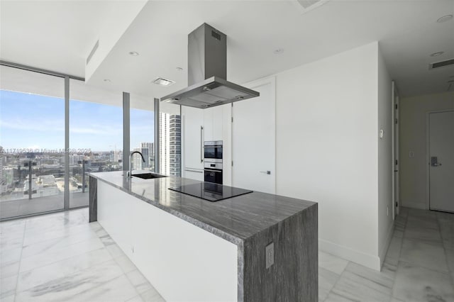 kitchen with black electric stovetop, island range hood, a spacious island, sink, and a wall of windows