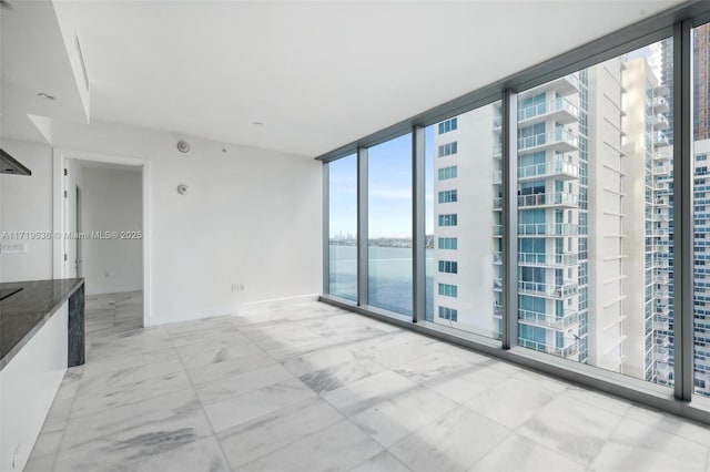 spare room with a water view and expansive windows