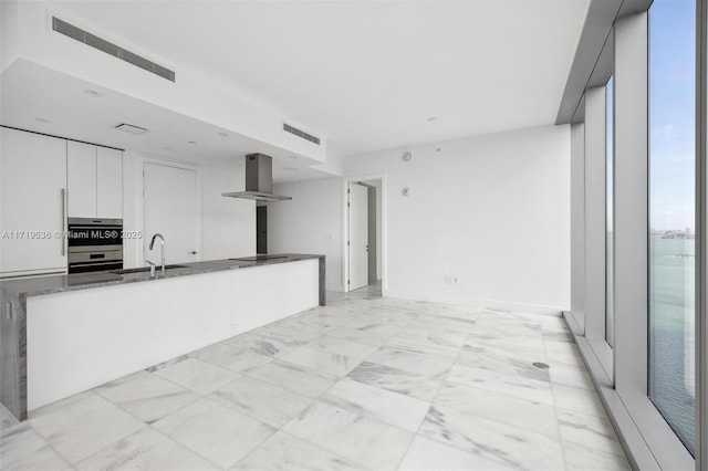 kitchen with white cabinetry, sink, wall chimney exhaust hood, double oven, and black electric cooktop